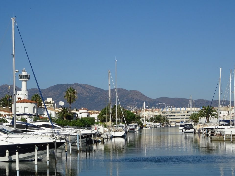 Canal de Empuriabrava con veleros amarrados y el faro al fondo